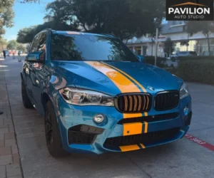 view of a luxury car parked inside a brightly lit detailing garage, showcasing a flawless, high-gloss finish after a paint protection film installation