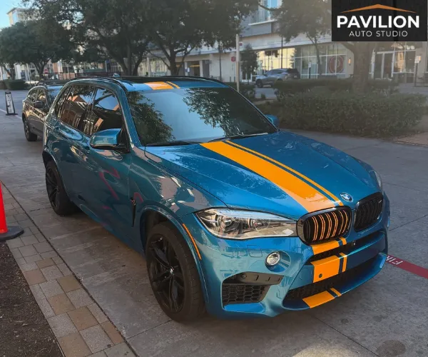 view of a luxury car parked inside a brightly lit detailing garage, showcasing a flawless, high-gloss finish after a paint protection film installation